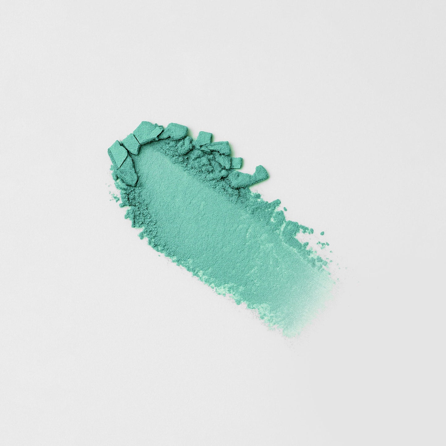 Green-teal pressed eyeshadow swatch with chunky, textured streak