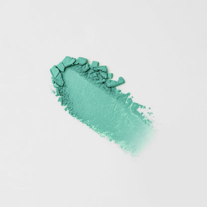 Green-teal pressed eyeshadow swatch with chunky, textured streak