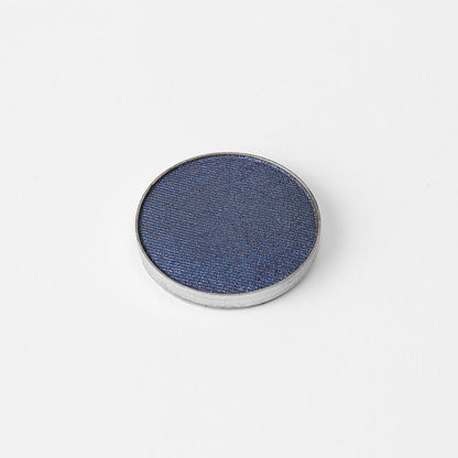 Pressed eyeshadow pan, dark blue shimmer in a round compact.