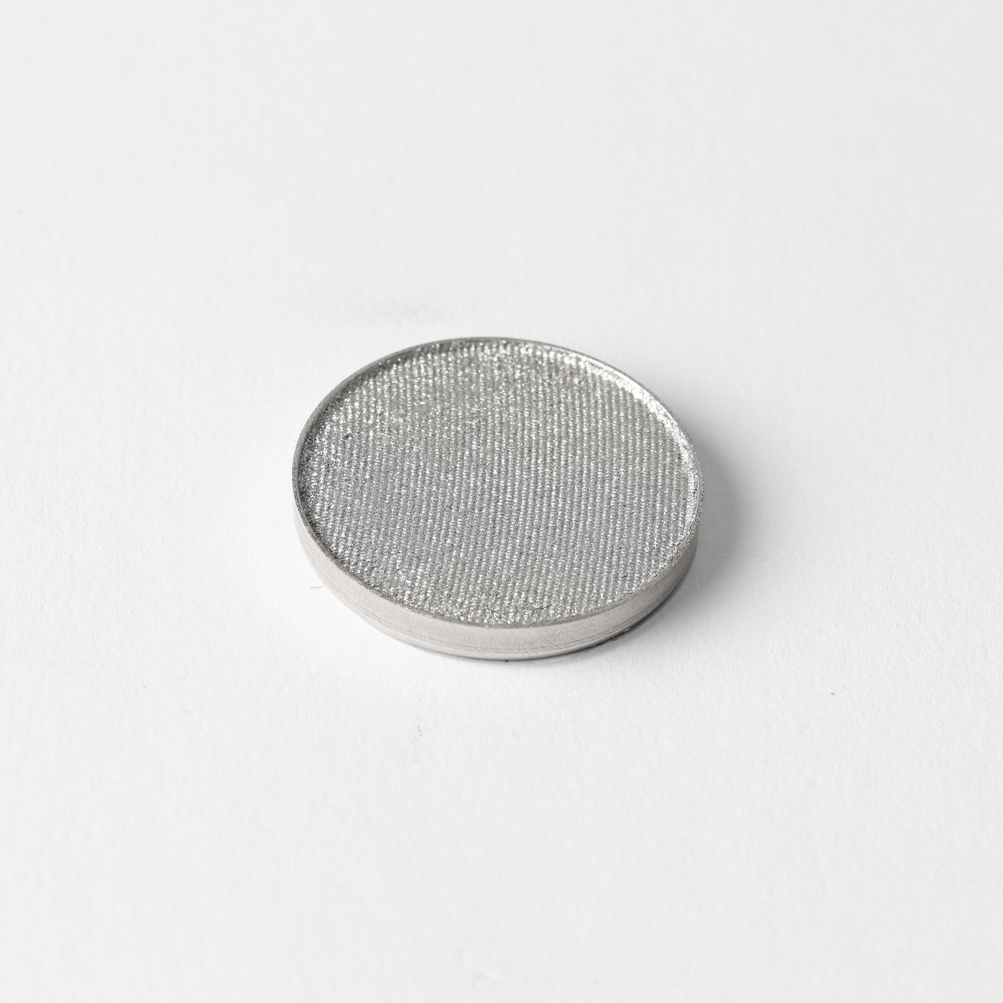 Pressed eyeshadow pan with shimmering silver-gray color