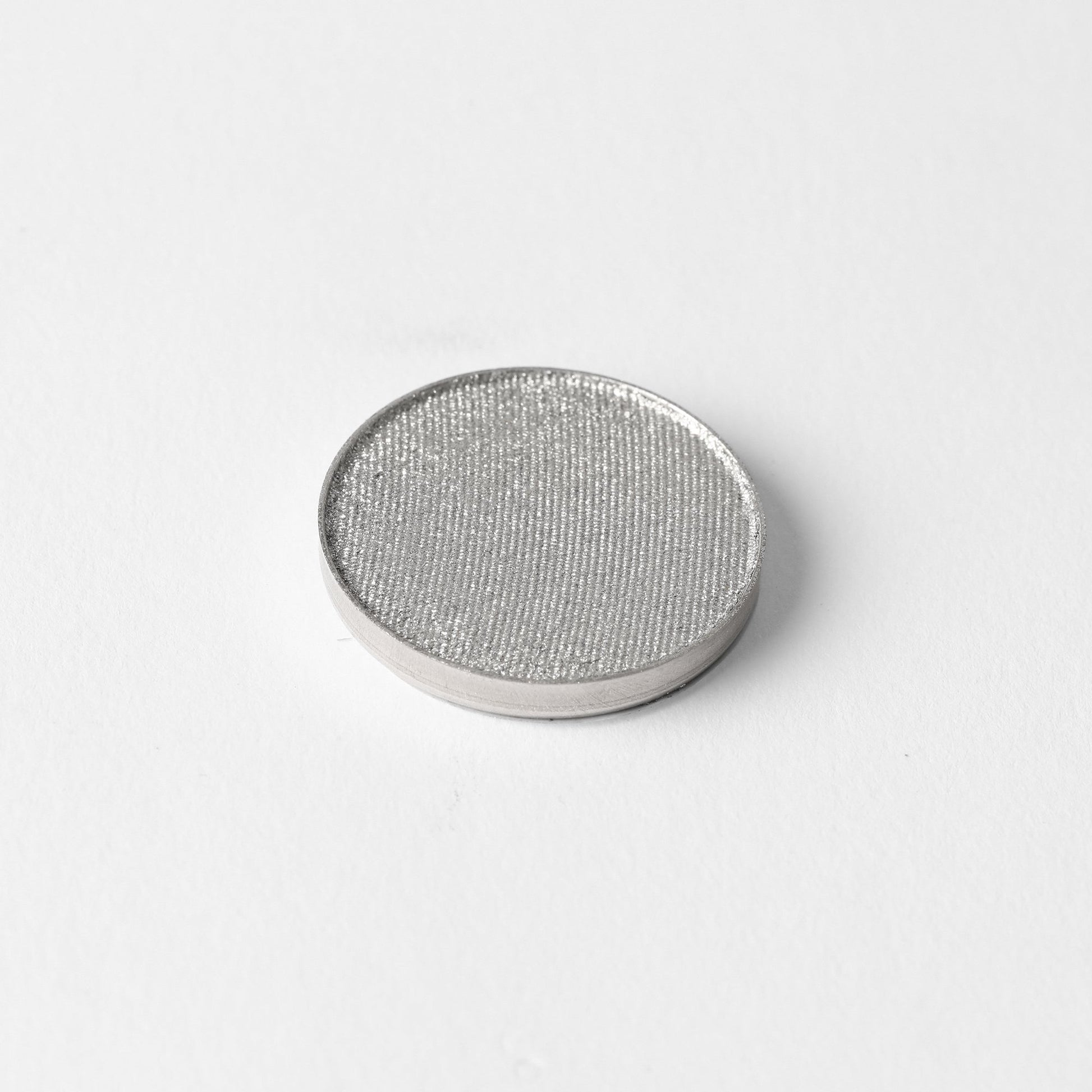Pressed eyeshadow pan with shimmering silver-gray color