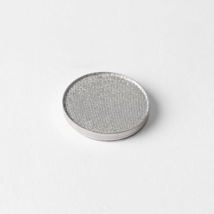 Pressed eyeshadow pan with shimmering silver-gray color