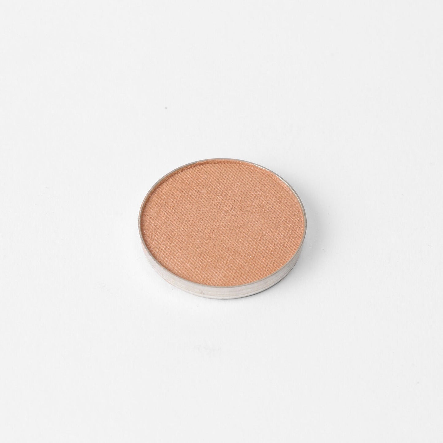 Pressed eyeshadow pan with warm apricot shimmer finish, round compact.