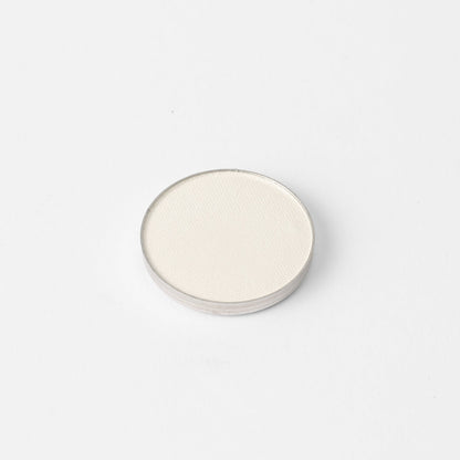 Round pressed eyeshadow pan with light shimmering neutral shade