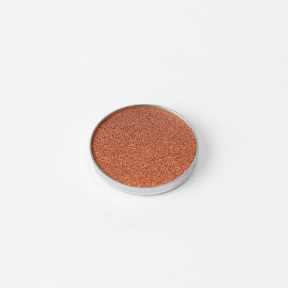 Pressed eyeshadow pan with copper rose-brown shimmer in a round compact