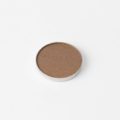 Pressed eyeshadow pan with matte bronze-tan shade in a round compact.