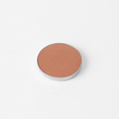 Pressed eyeshadow pan with peachy taupe shimmer in a round compact
