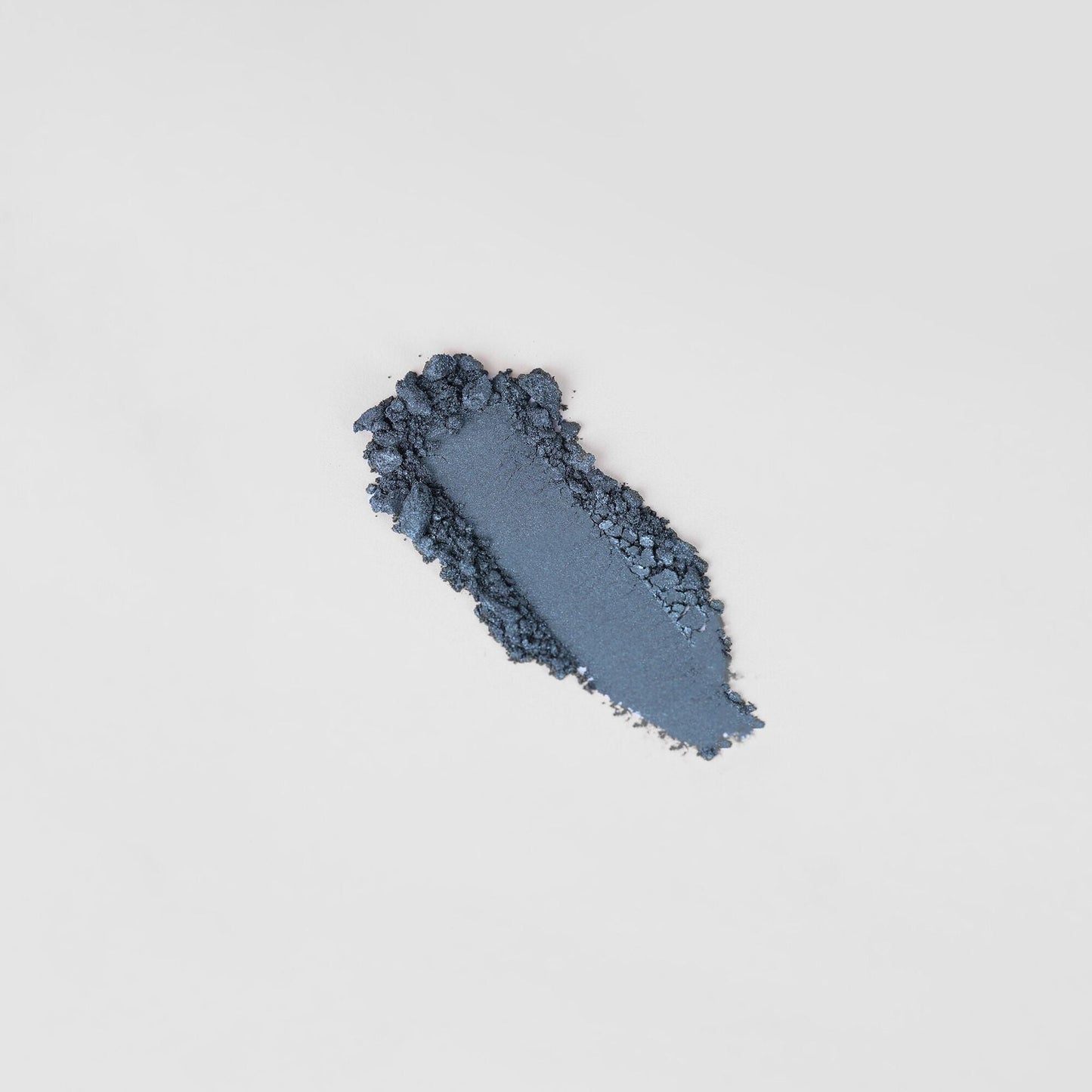 Pressed eyeshadow swatch, dark navy-blue shimmer with soft powder texture.