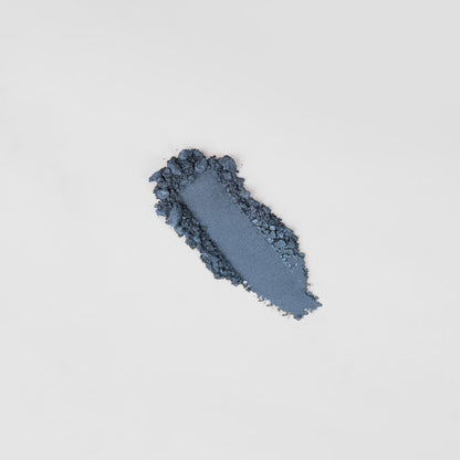 Pressed eyeshadow swatch, dark navy-blue shimmer with soft powder texture.
