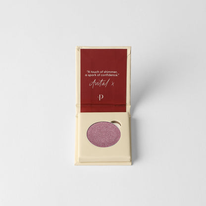 Pressed eyeshadow pan with mauve-purple shimmer, in open case