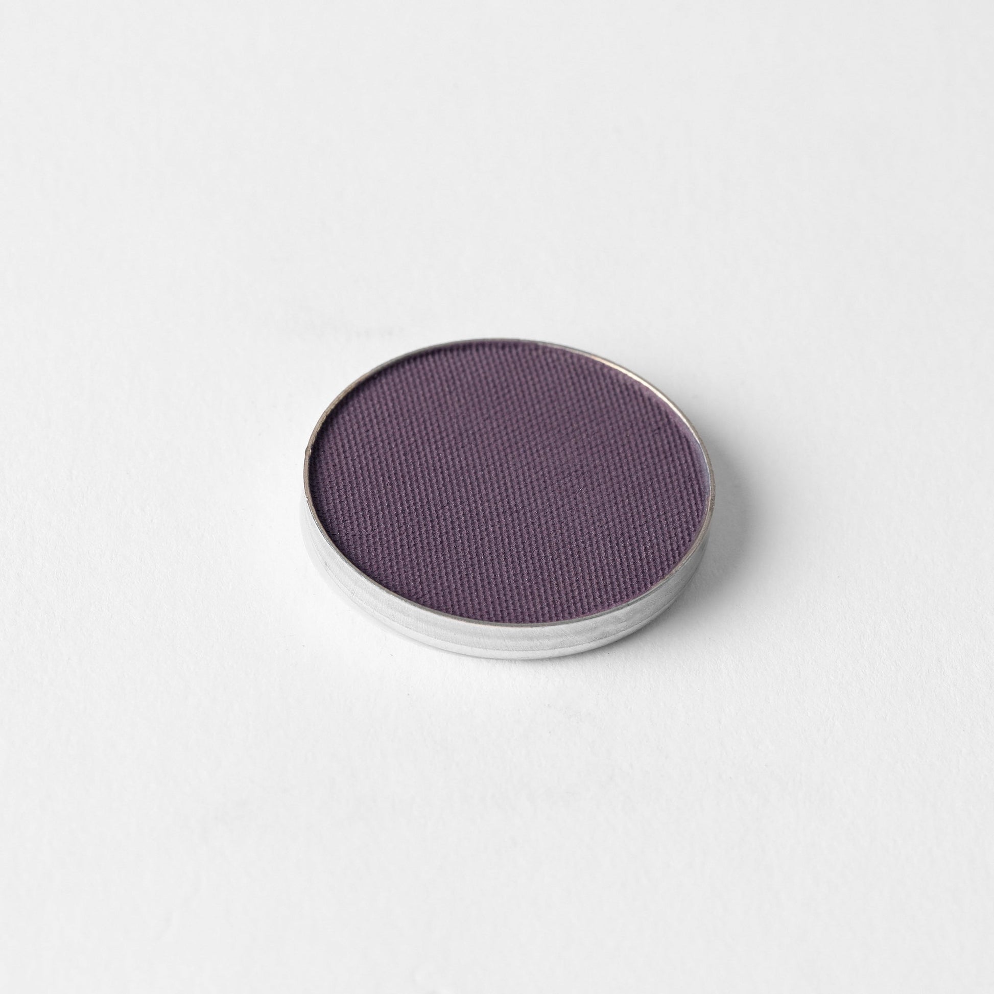 Pressed eyeshadow pan, plum purple matte powder.