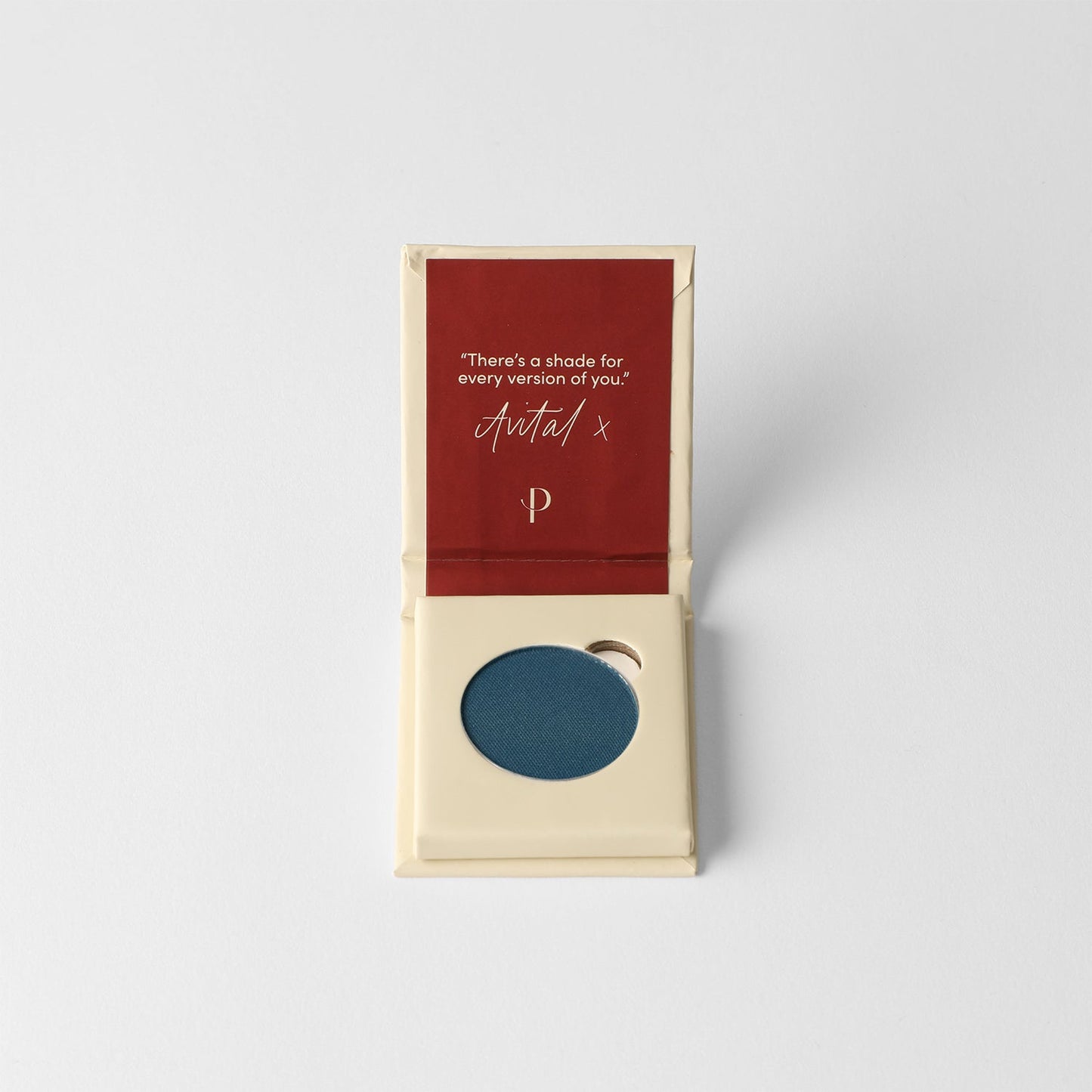 Pressed eyeshadow compact with dark blue matte pan in open box.