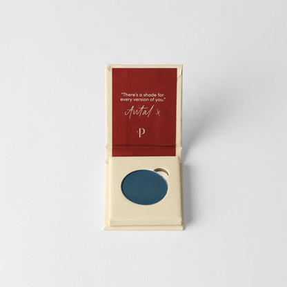 Pressed eyeshadow compact with dark blue matte pan in open box.