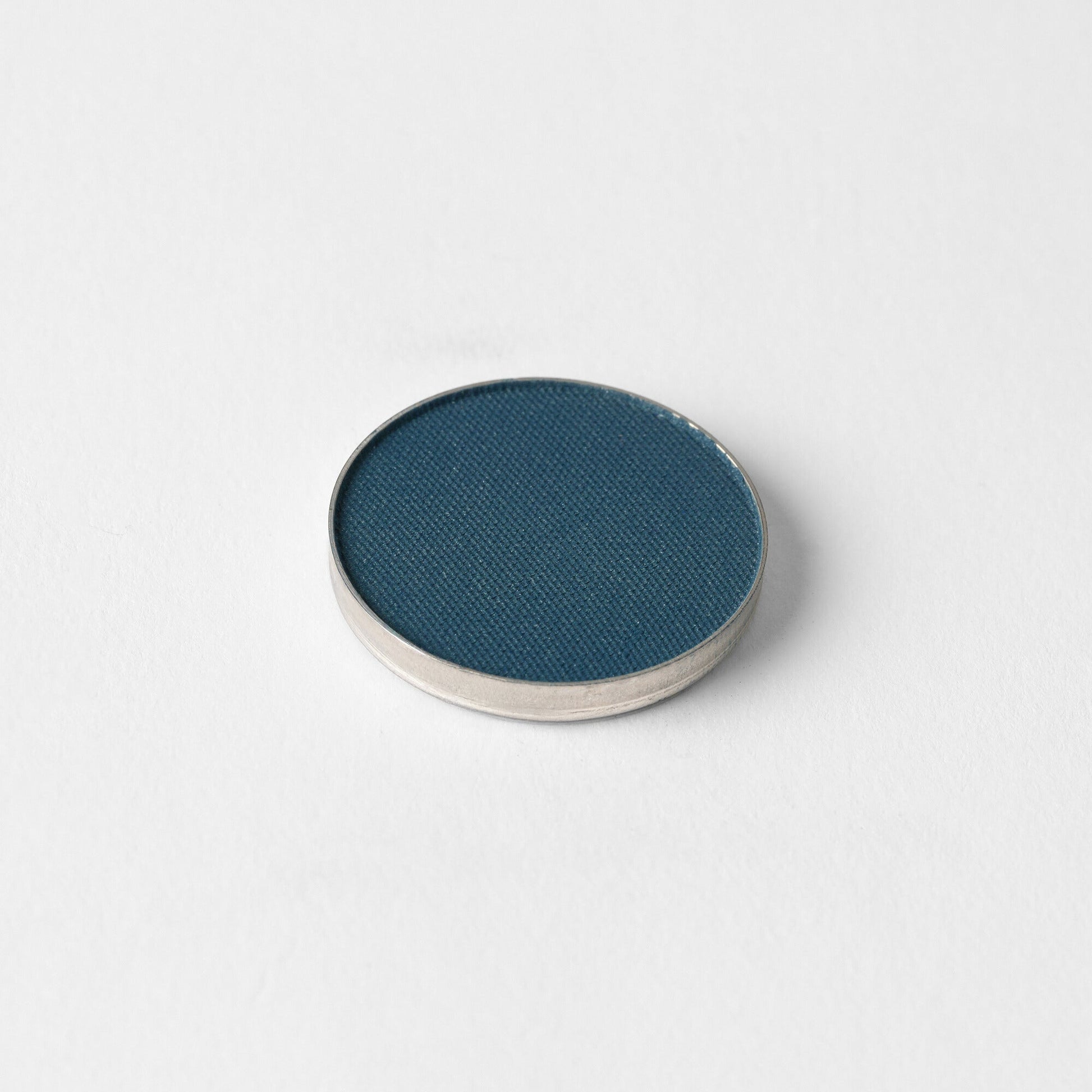 Pressed eyeshadow pan, dark blue matte powder.