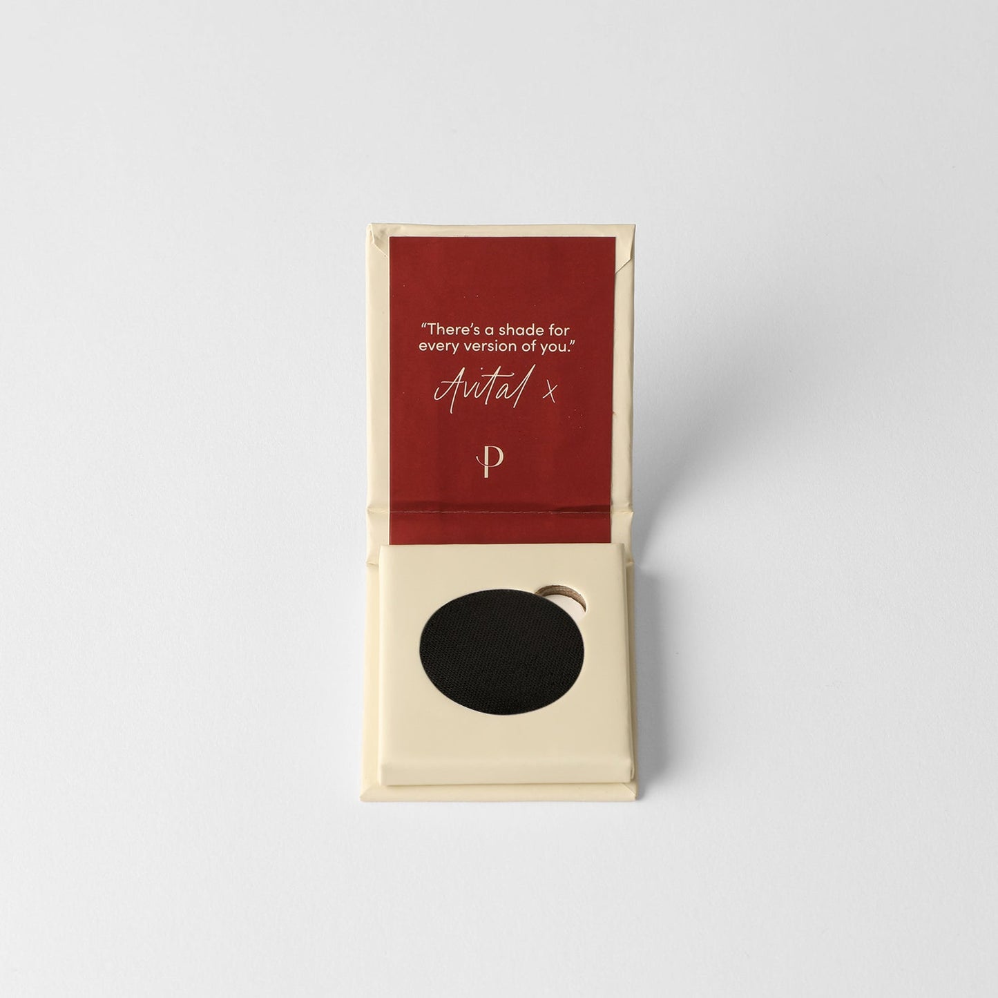 Pressed eyeshadow compact with black matte pan in open box.