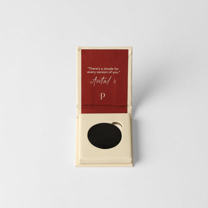 Pressed eyeshadow compact with black matte pan in open box.