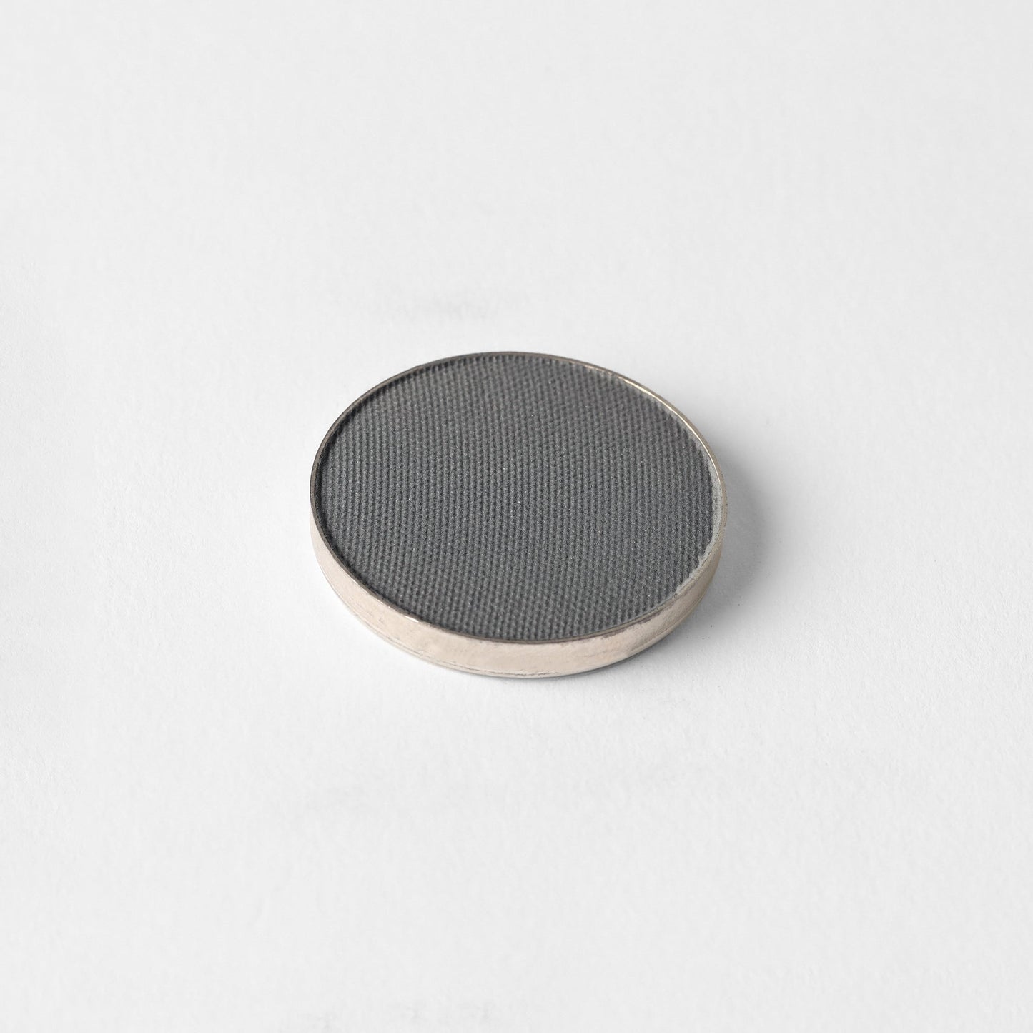 Matte pressed eyeshadow compact, dark gray pan with textured surface