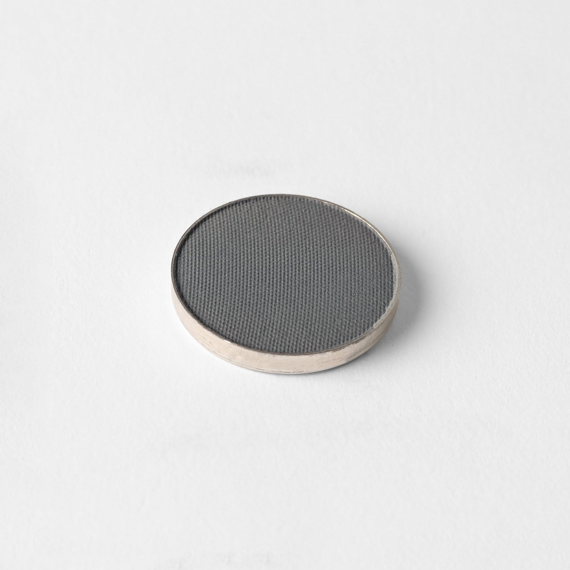Matte pressed eyeshadow compact, dark gray pan with textured surface