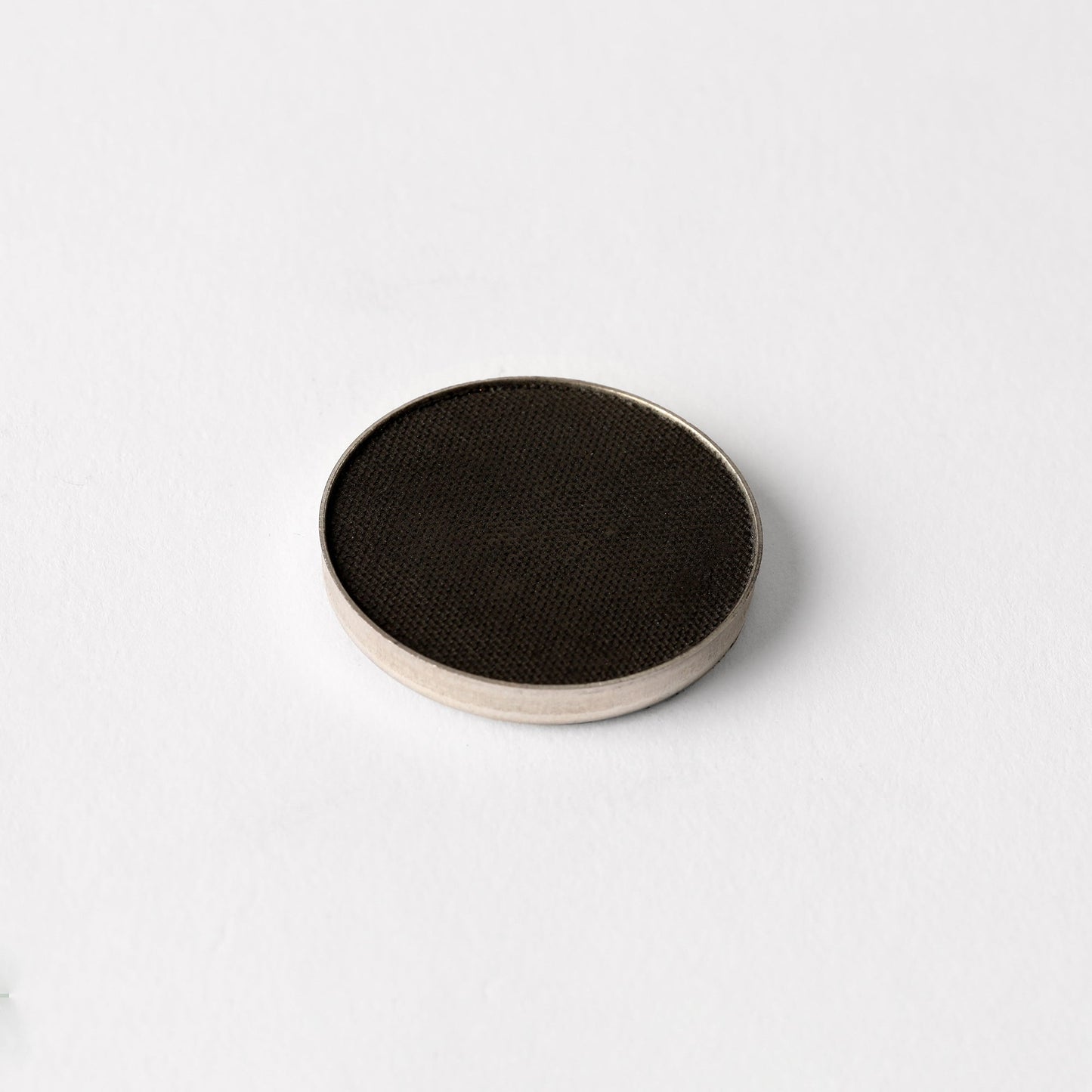 Matte pressed eyeshadow compact, solid black pan with textured surface