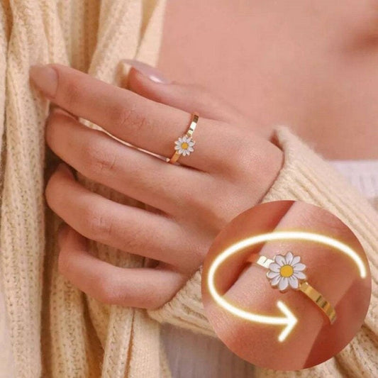 Rotatable daisy fidget spinner ring with white flower and gold band on finger