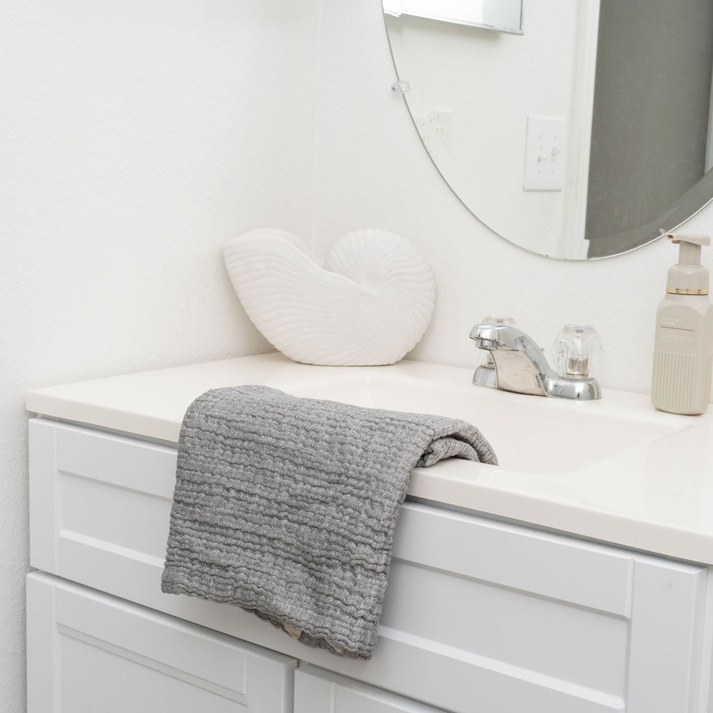 Gray terry towel folded on a bathroom sink counter