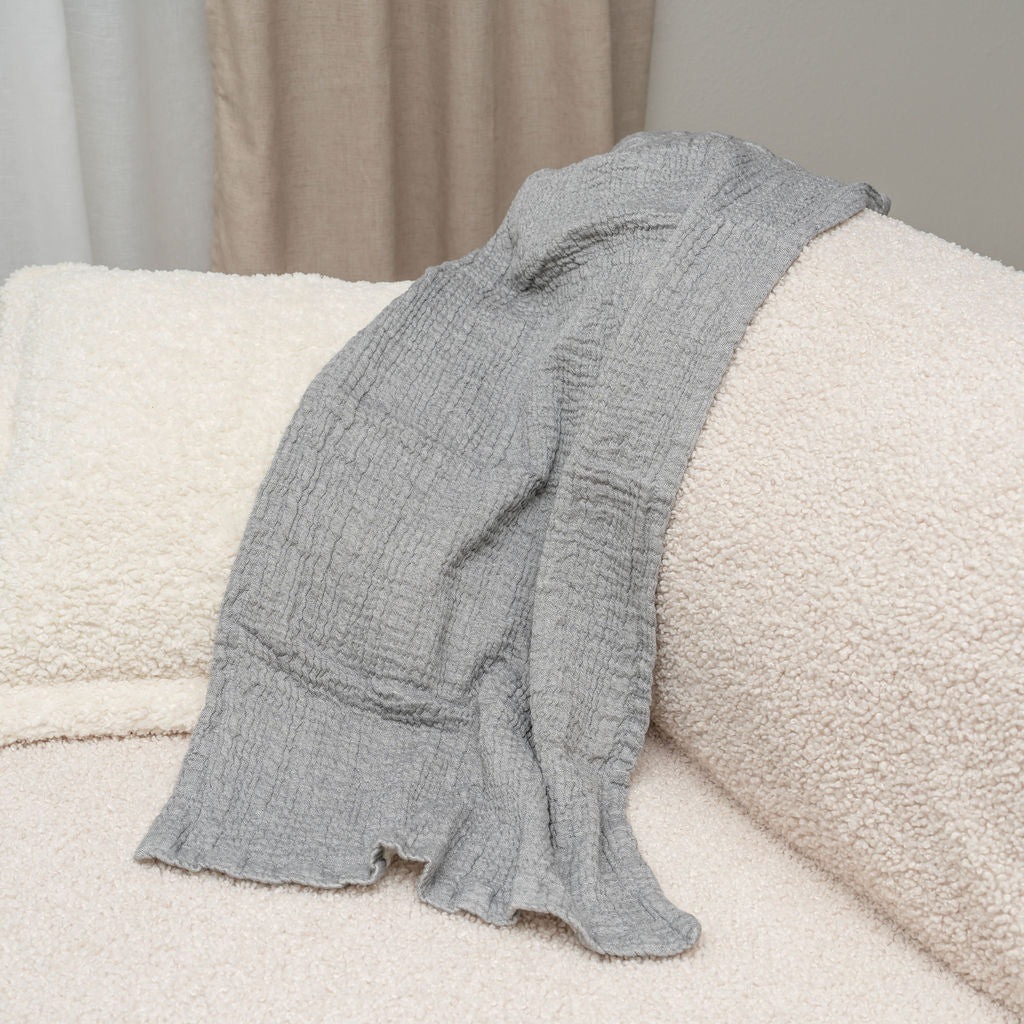 Gray towel draped over a cream couch cushion