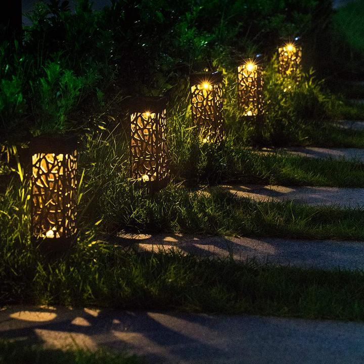 Black cutout solar garden lights glowing along a garden walkway