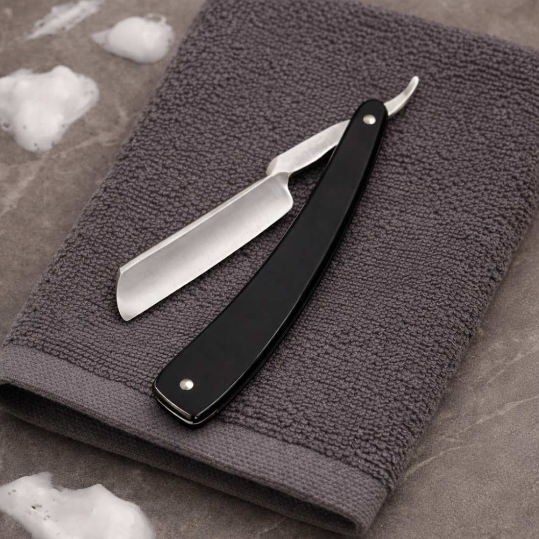 Straight razor on gray towel, black handle with silver blade