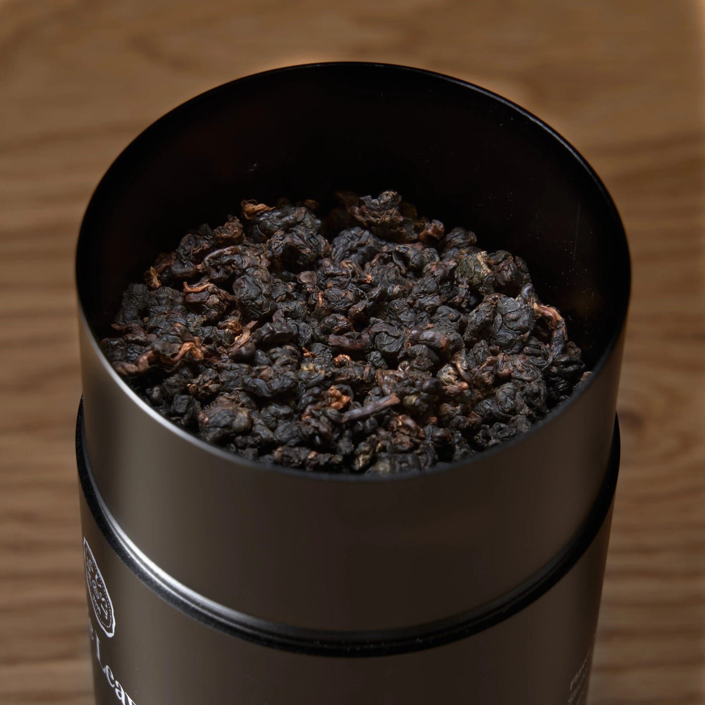 Dark roasted oolong tea leaves in open stainless canister