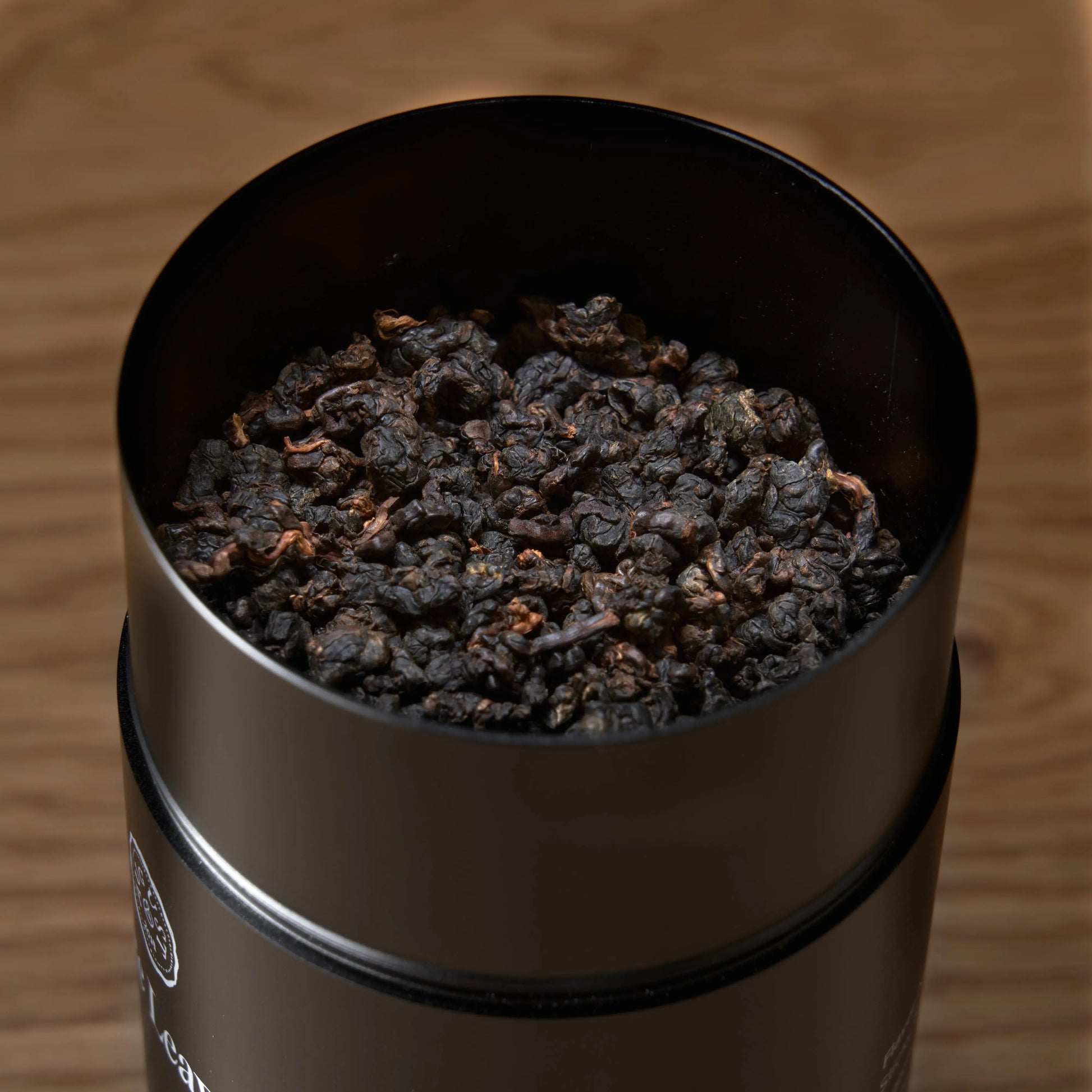 Dark roasted oolong tea leaves in open stainless canister