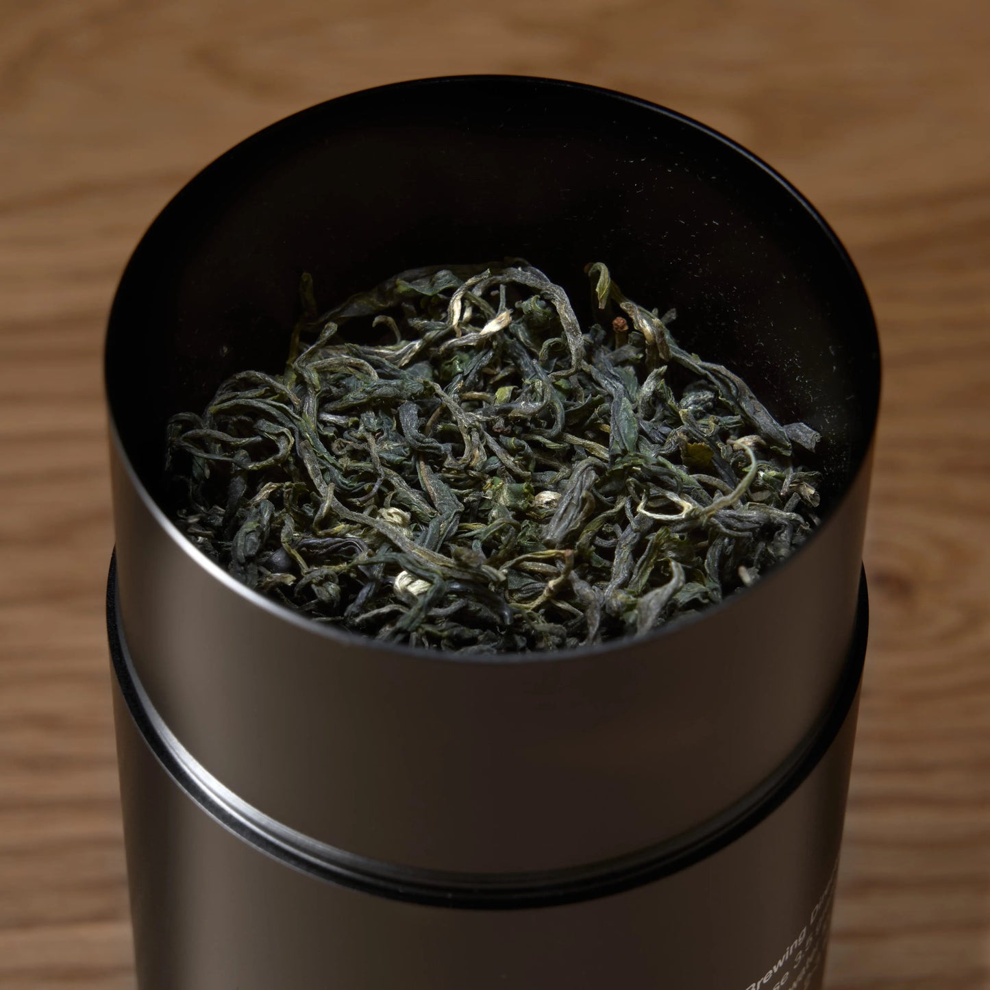 Emerald green tea leaves in a dark metal scoop
