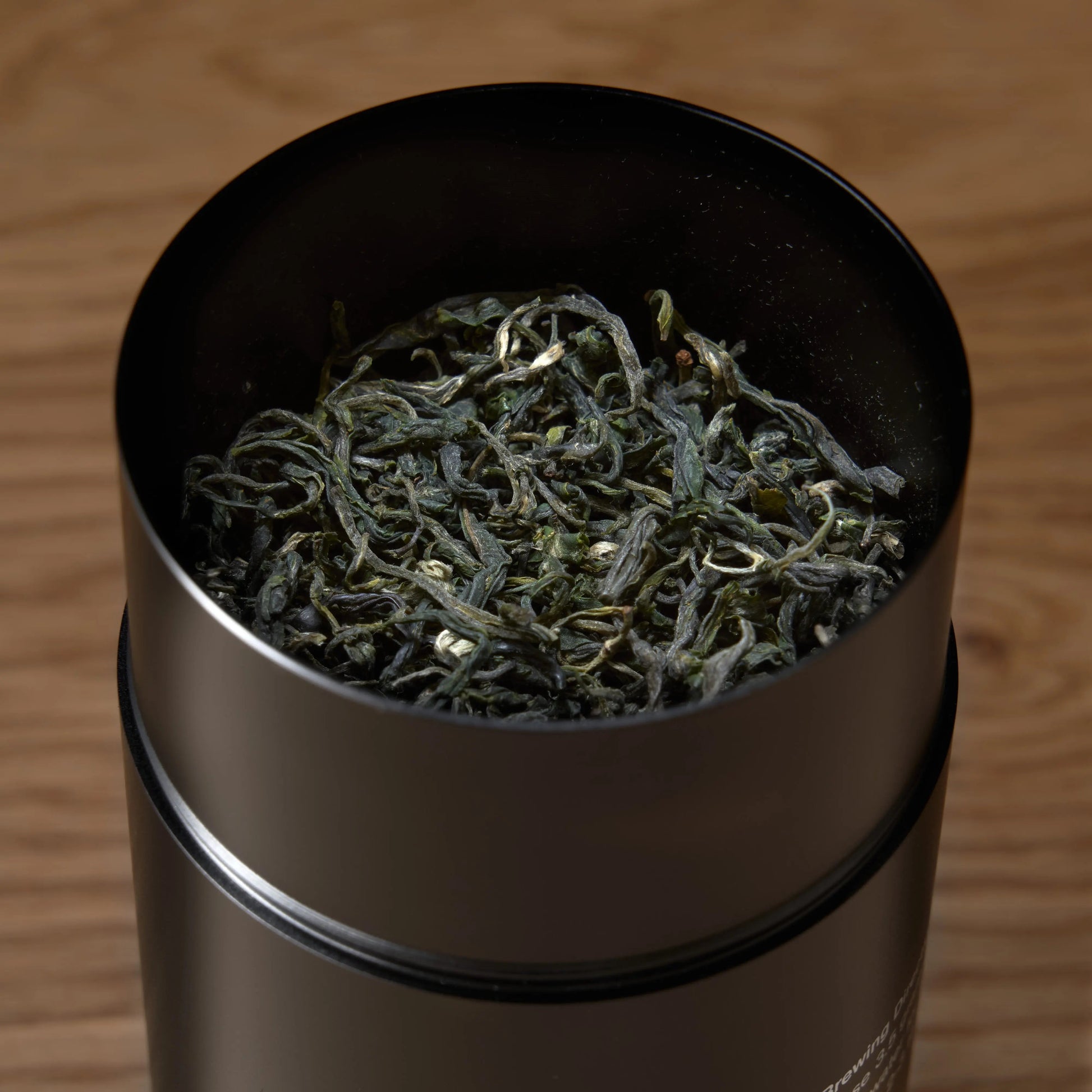 Emerald green tea leaves in a dark metal scoop