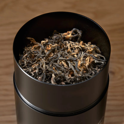 Gold black tea leaves, loose tea in a black cylinder scoop