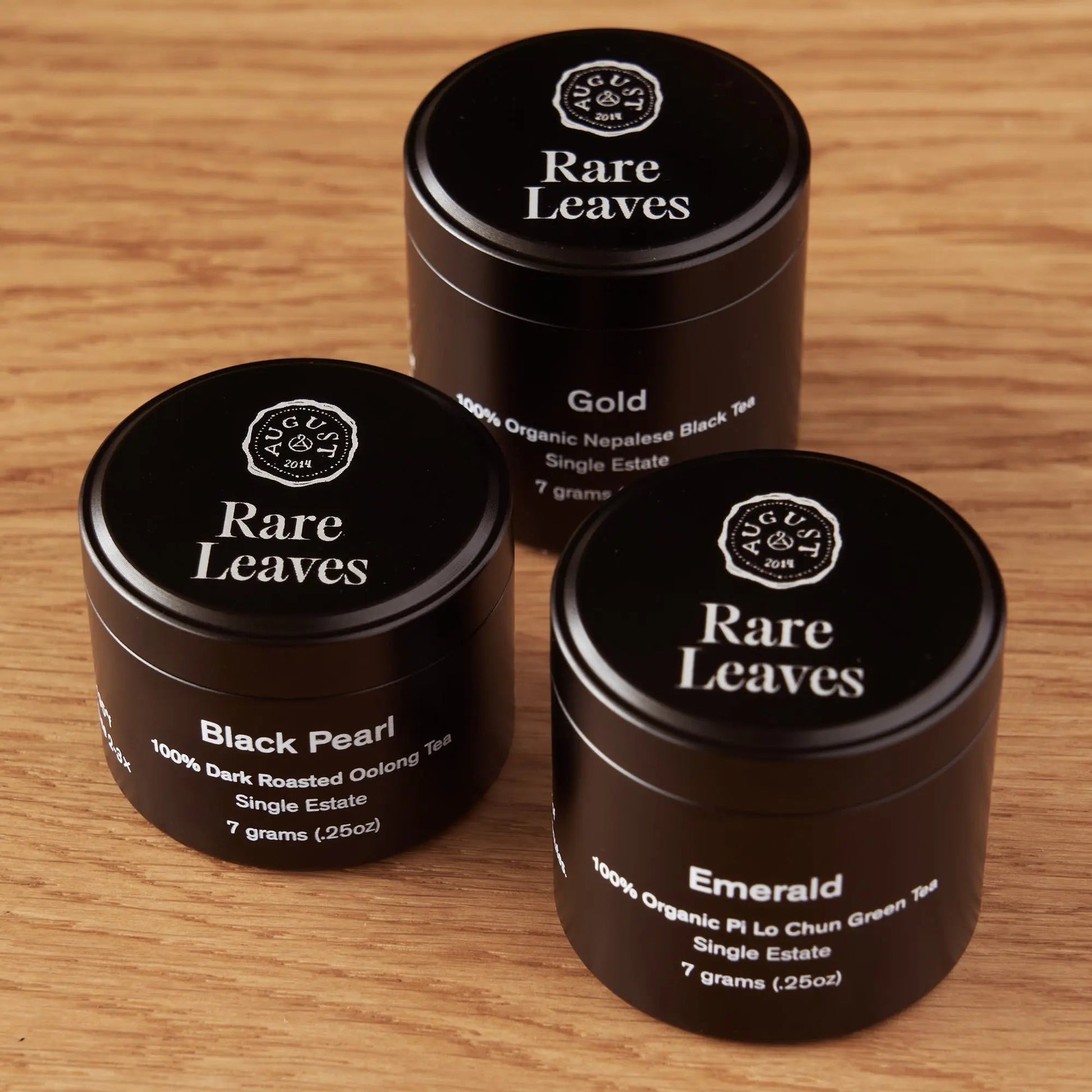 Tea mini tins on table: Gold, Black Pearl, and Emerald by Rare Leaves.