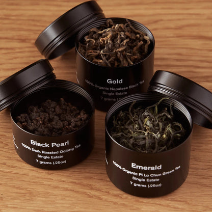 Three open tea mini tins with loose leaves: Black Pearl, Gold, Emerald.