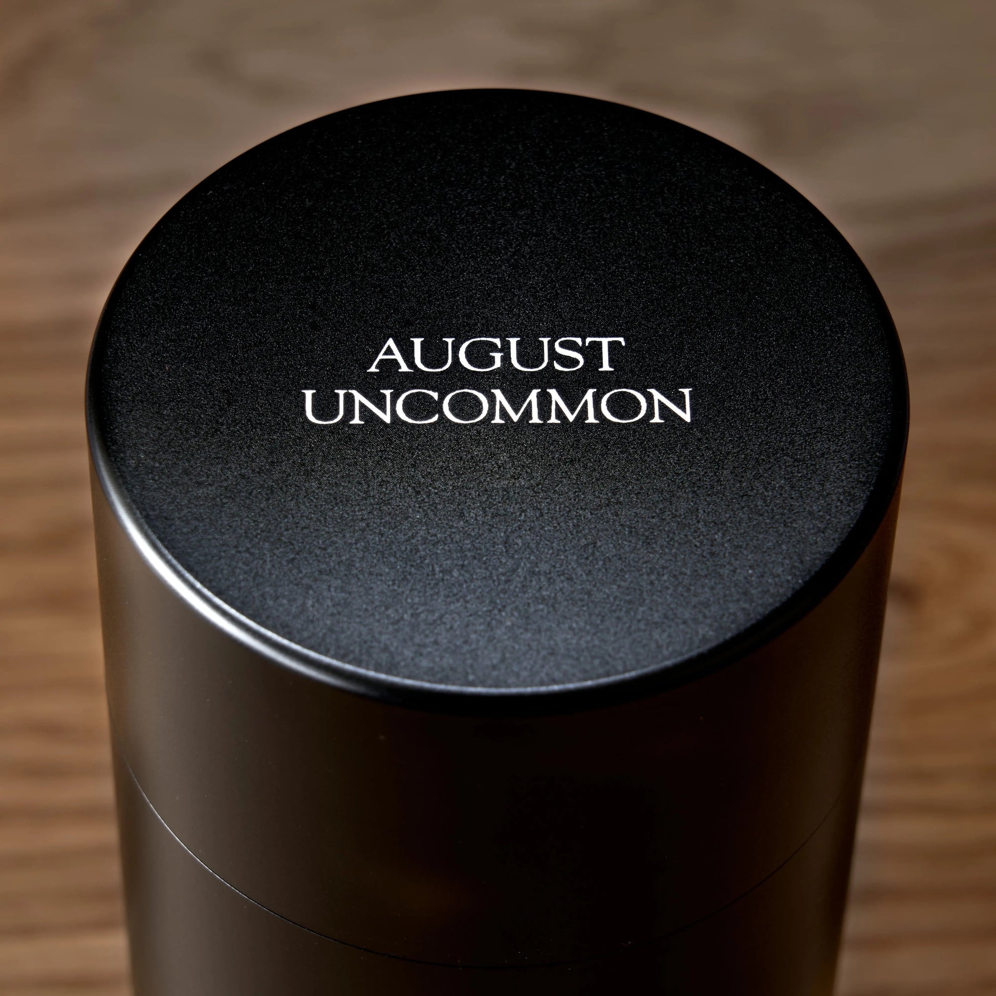 Black oolong tea tin lid with AUGUST UNCOMMON text