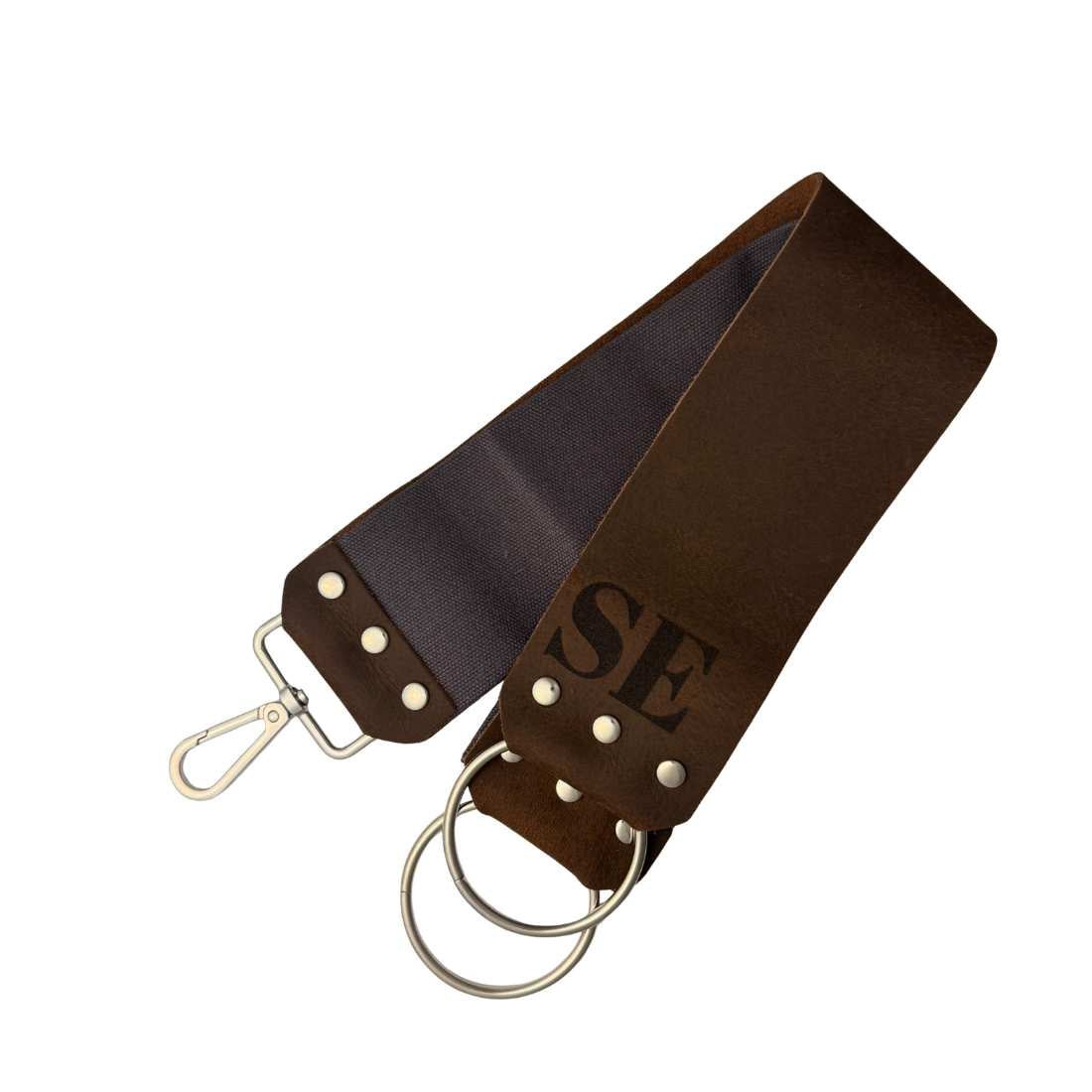 Dark brown leather razor strop with brass keyring and riveted strap ends