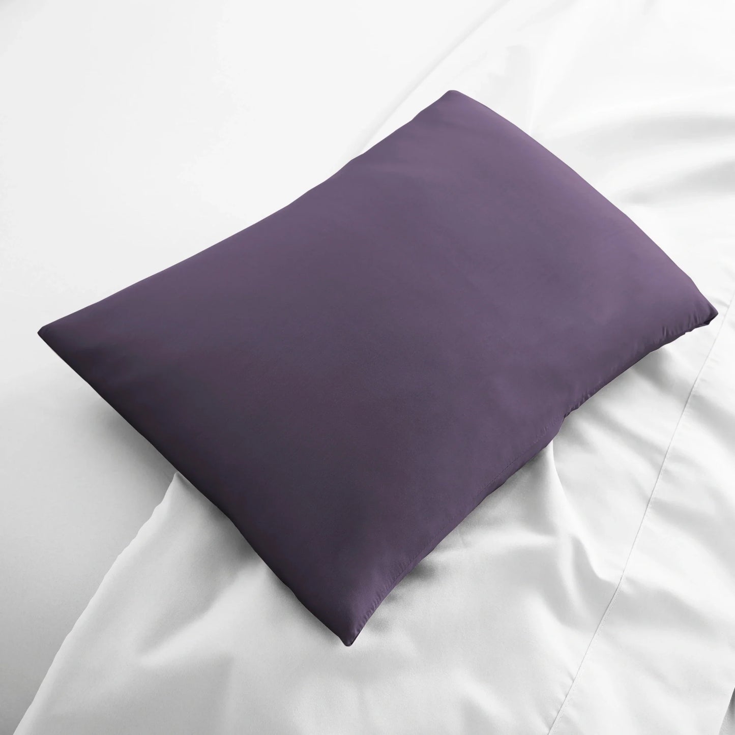 Dark purple travel pillowcase, smooth fabric folded on bed