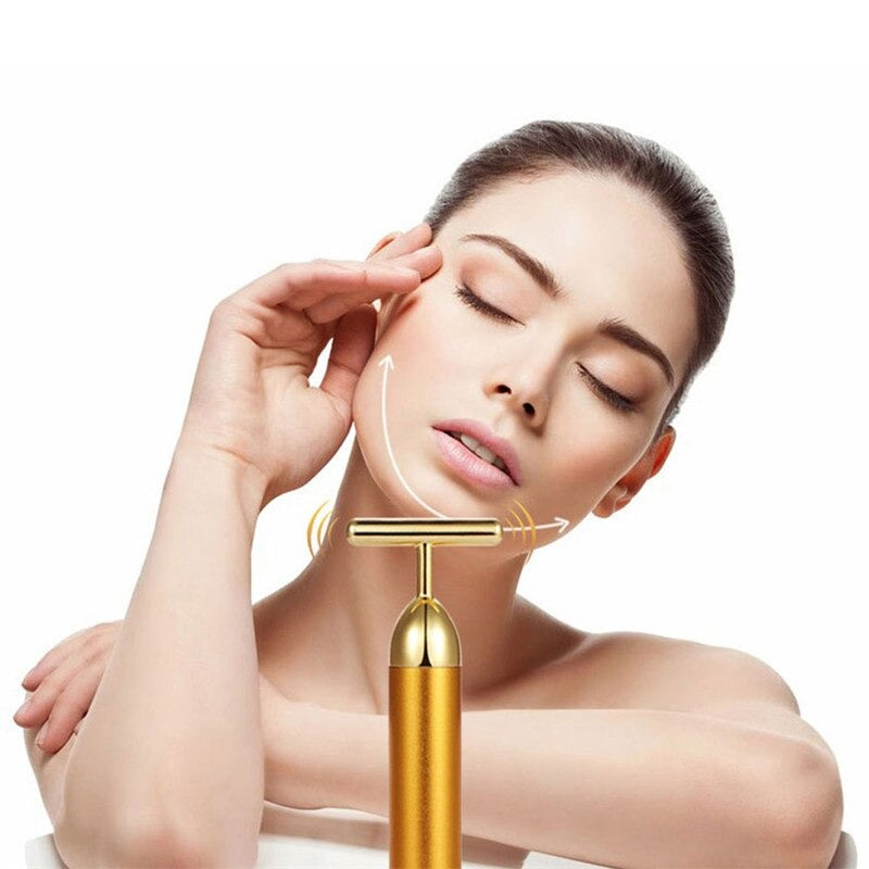Gold facial roller massager with T head, applied along cheek and jaw