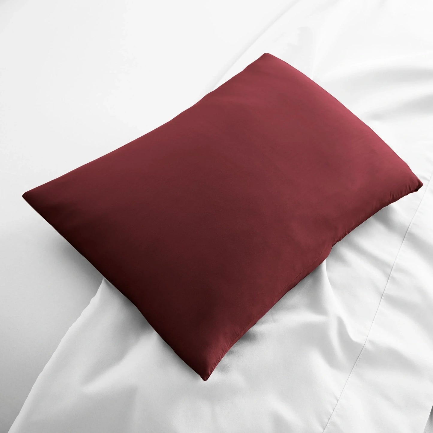 Deep red travel pillowcase, smooth fabric folded on bed