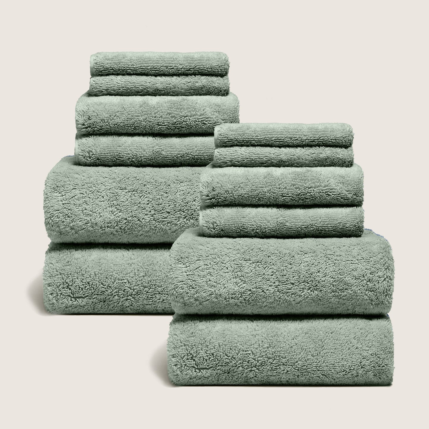Set of dark green plush towels stacked and folded, soft terry loops