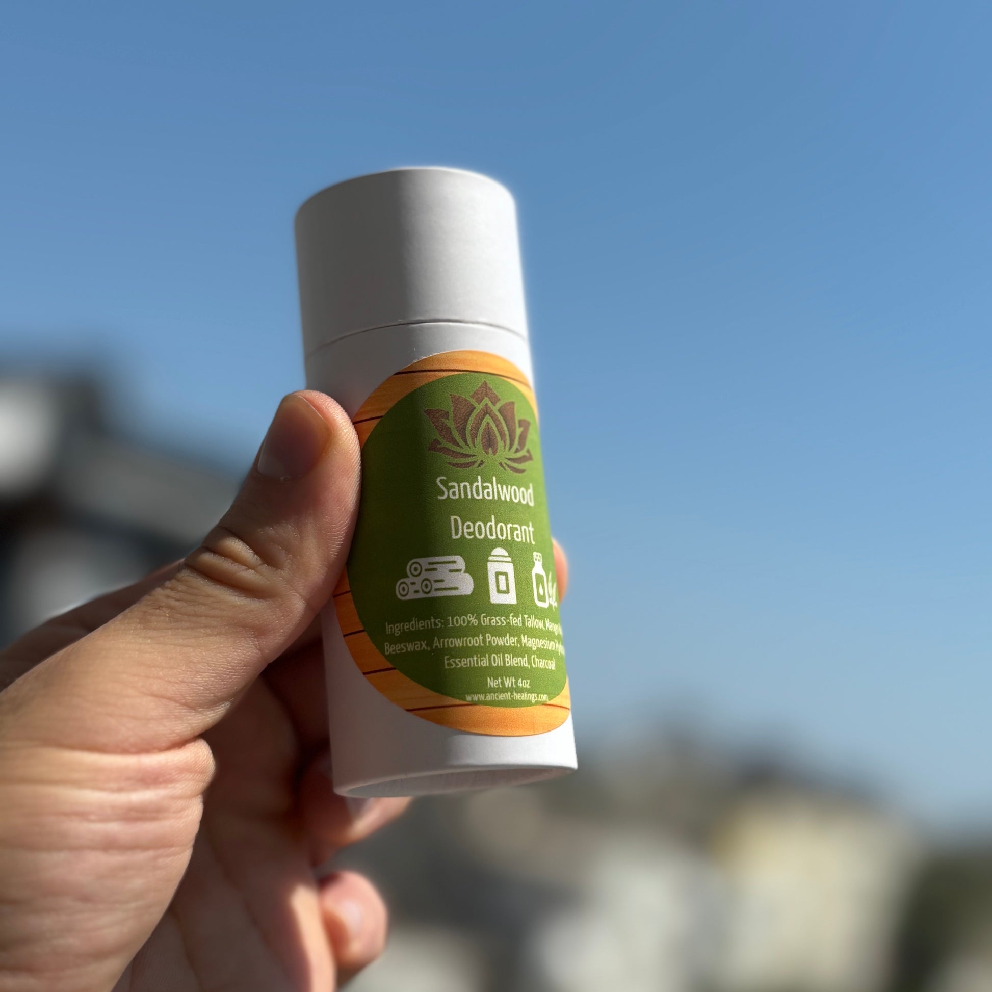 Deodorant stick with silver top and green Sandalwood label held in hand