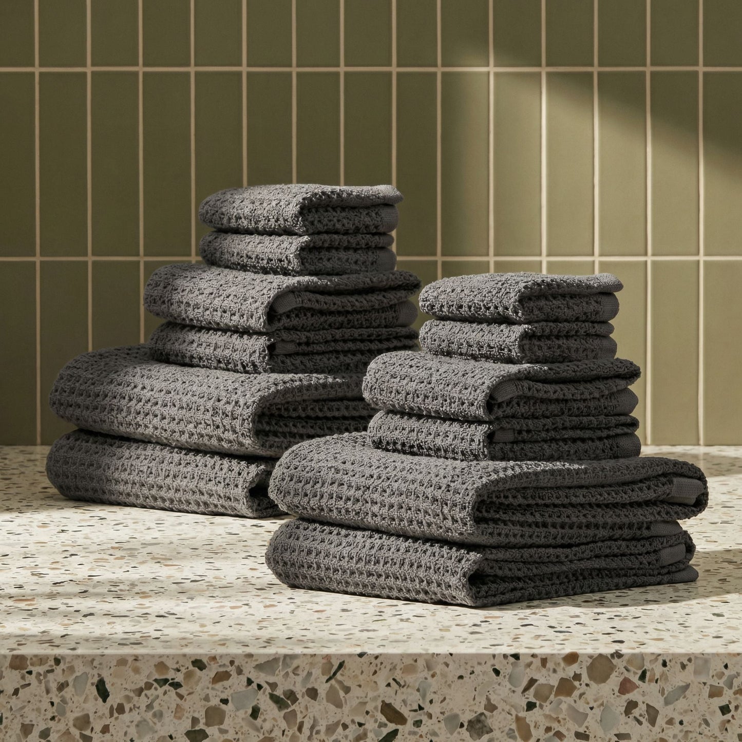 Charcoal waffle weave towels stacked in neat piles, textured grid weave