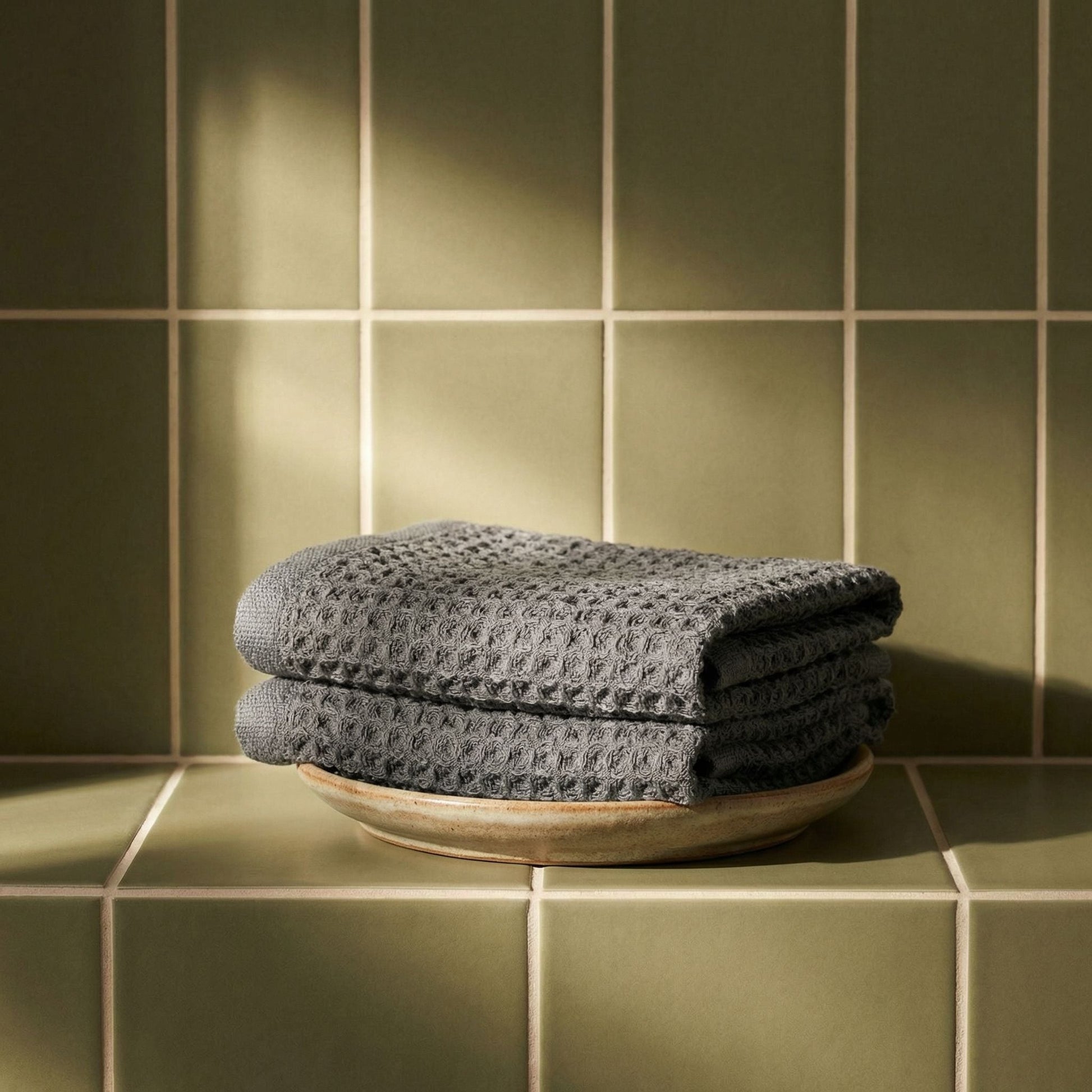 Charcoal waffle cotton towels, folded into a neat stack with textured pattern.