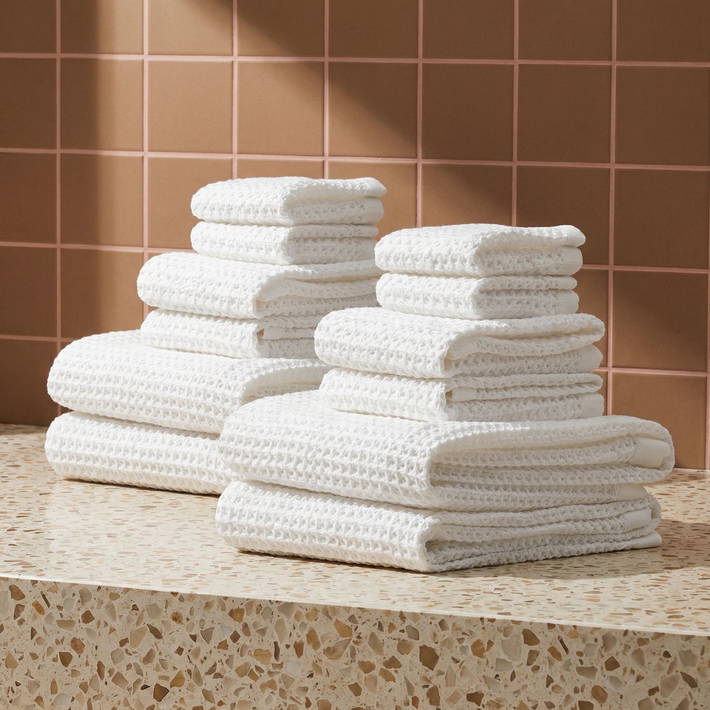 White waffle cotton towel set stacked and folded on a countertop, textured weave.