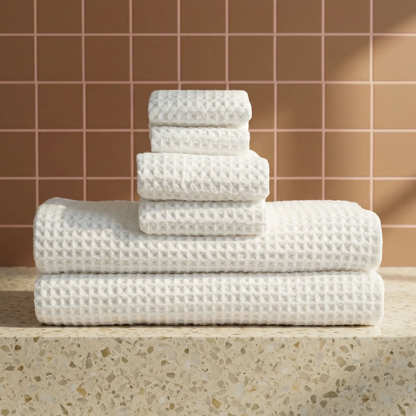 White waffle cotton towels folded in a stack on a countertop, textured waffle pattern.