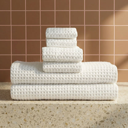 White waffle cotton towels folded in a stack on a countertop, textured waffle pattern.