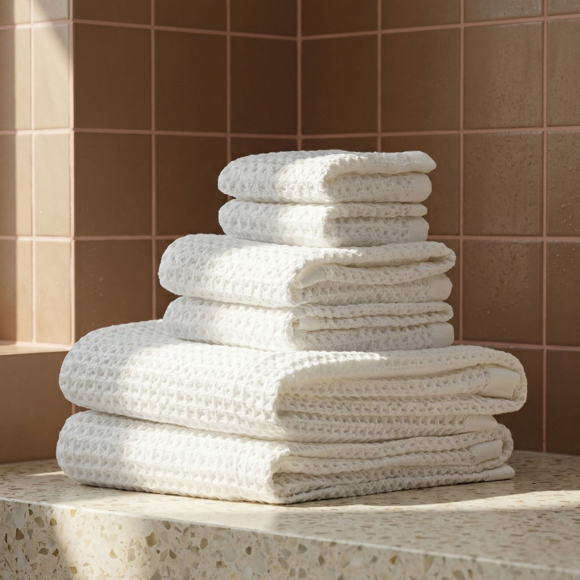 White waffle cotton towels stacked on a countertop with visible waffle texture.