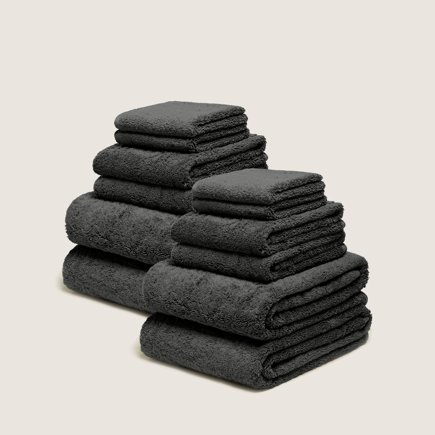 Stack of folded plush towels, dark gray charcoal, dense terry loop pile.