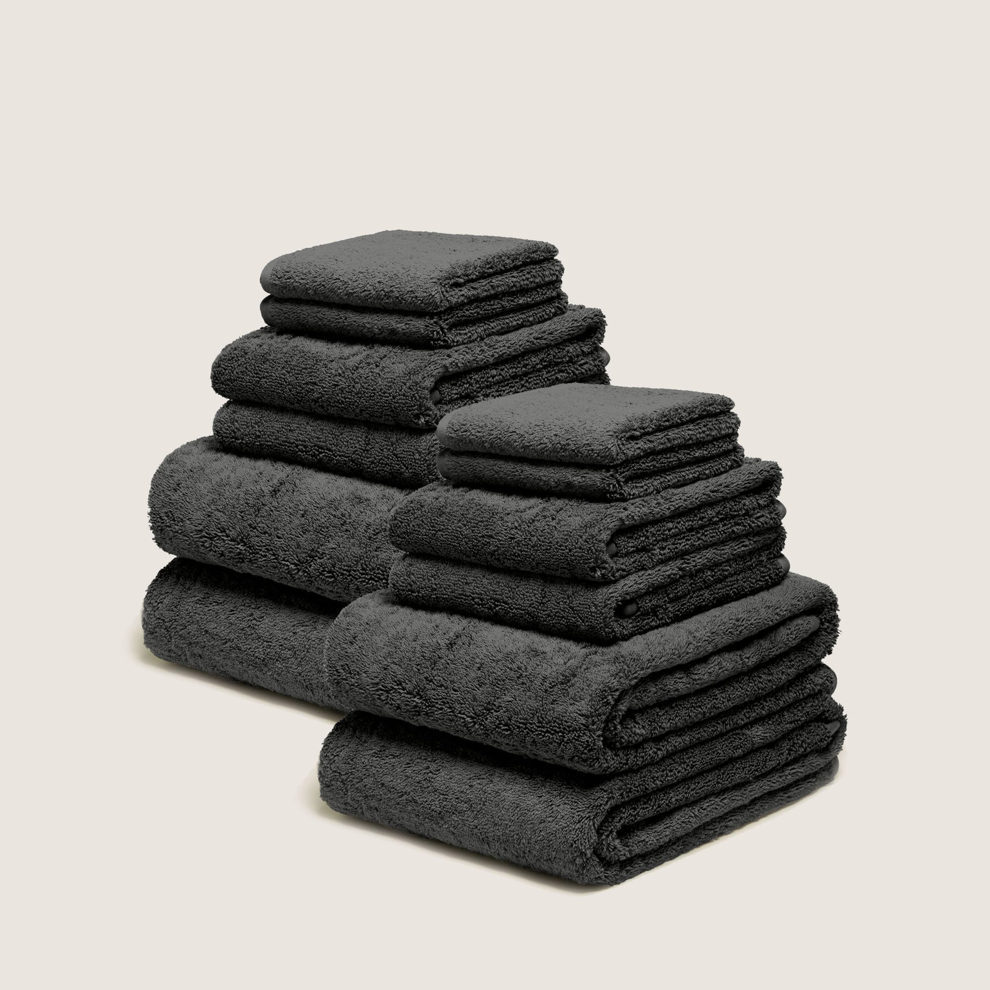 Stack of folded plush towels, dark gray charcoal, dense terry loop pile.